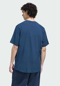 Tmavomodré tričko s krátkym rukávom, vybavené okrúhlym výstrihom, hladkou textúrou, raglánovými rukávmi a zaoblenými bočnými švami pre lepšiu pohyblivosť.