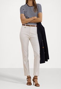 Randig marinblå och vit t-shirt, krämfärgade skräddarsydda byxor, brun bälte med guldfäste, marinblå blazer och bruna högklackade sandaler.