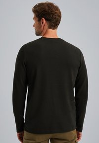 Langarmshirt aus dunkelgrüner Baumwolle, geripptem Material, runden Halsausschnitt und geradem Schnitt. Verfügt über minimale Nähte und seitliche Schlitze.