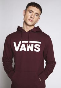 Bordový mikina vyrobená z mäkkej tkaniny, s veľkým bielym logom "VANS" na hrudi a s kapucňou na šnúrky. Obsahuje klokanie vrecko.