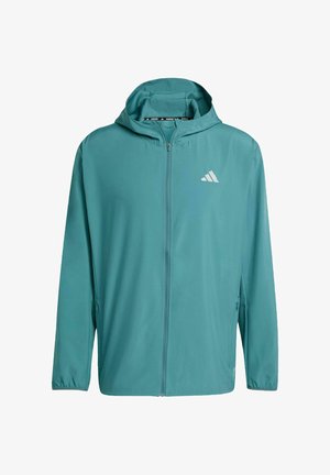 Chaqueta ligera color verde azulado con cremallera y capucha, fabricada con tejido suave. Presenta un logo blanco en el lado izquierdo del pecho y puños elásticos.