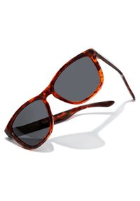 Ochelari de soare tortoiseshell maro cu lentile închise, formă unghiulară și brațe late. Cadru din plastic cu un finisaj lucios și margini ușor curbate.