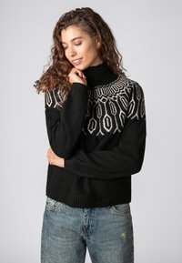 Schwarzer Strickpullover mit hohem Kragen, der ein geometrisches Muster in hellgrau auf den Schultern aufweist. Weiche Textur, lockere Passform, gerippte Bündchen und Saum.