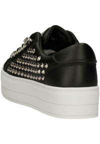 Sneaker in pelle nera con dettagli in metallo argentato, suola bianca spessa e design affusolato con finiture testurizzate lungo il lato.