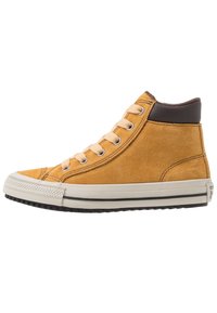 Zapatillas altas de ante mostaza con cordones beige, tobillo de cuero marrón, suela de goma y puntera texturizada. Diseño simple y clásico.