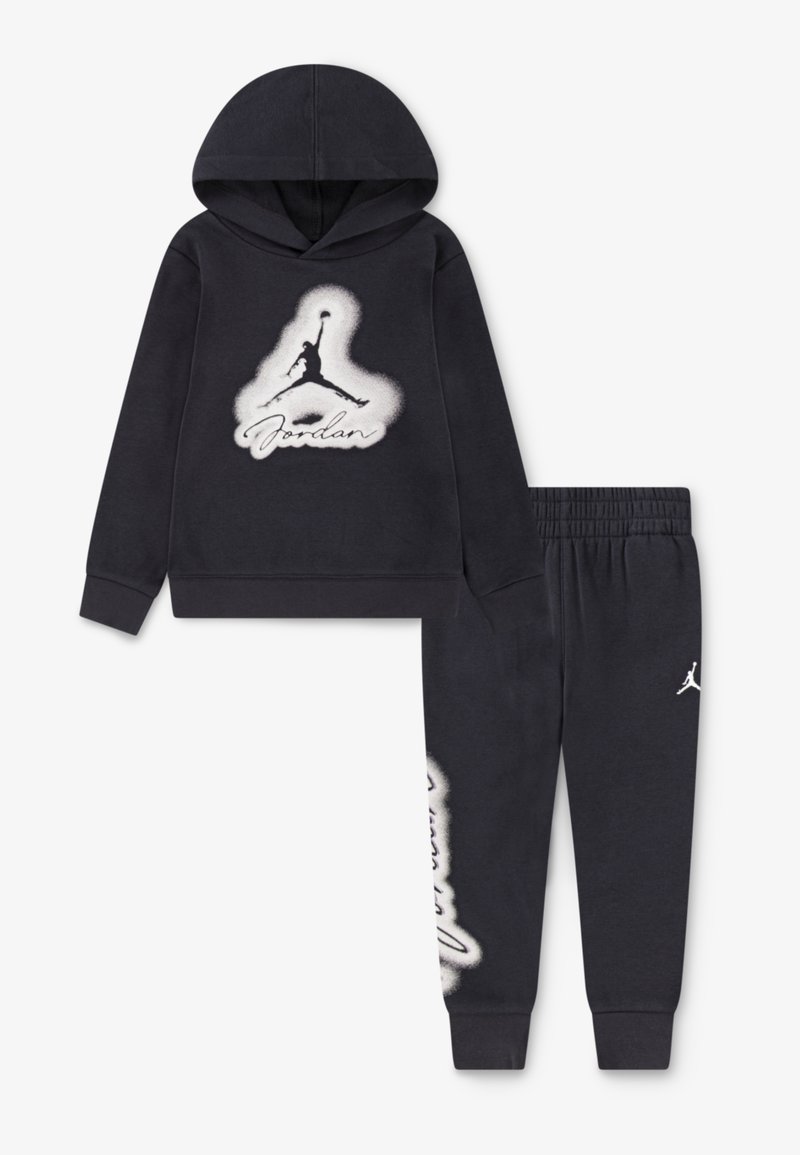 Ensemble de sweat à capuche et pantalon de jogging bleu marine foncé, présentant un grand logo Jordan blanc et un texte sur le devant. Tissu doux avec des poignets et une taille côtelés.