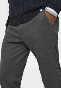Un pantalon de survêtement gris en tissu doux, doté de poches latérales et d'une coupe décontractée, associé à un pull en tricot texturé bleu marine.