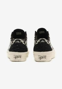 Sneakers a motivi bianco e nero con tomaia testurizzata, design slip-on, suola in gomma bianca e logo "Off the Wall" sul tallone.