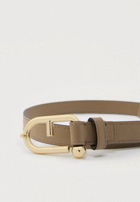 Vaaleanruskea nahkavyö, jossa on kullanvärinen D-kirjaimen muotoinen solki ja pallokoriste. Vöissä on siistit ompeleet ja sileä pinta.