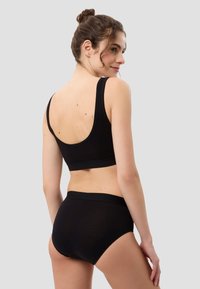 Schwarzer Sport-BH und hochgeschnittene Unterwäsche aus glattem Stoff. Der BH verfügt über breite Träger und ein abgerundetes Rücken-Design.