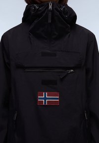 Giacca nera impermeabile con colletto alto, tasca con zip frontale, dettagli in velcro e patch ricamato della bandiera norvegese.