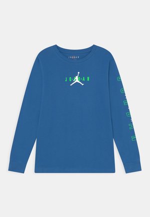 Blå langærmet Jordan skjorte med hvid Jumpman-logo og grøn tekst "JORDAN" på brystet samt grøn tekst ned langs højre ærme.