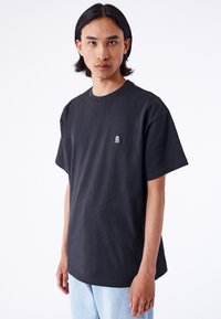 Sort bomulds t-shirt med grafisk tryk, rund halsudskæring og korte ærmer, med et lille hvidt logo på venstre bryst.