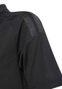 Trumpa juoda marškinėliai su dviem tamsiomis tekstūruotomis juostelėmis, einančiomis nuo peties iki apykaklės viršutinėje rankovėje.