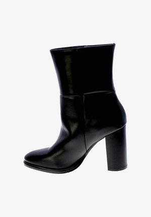 Botte de cheville en cuir noir au design épuré, avec un bout pointu et un talon épais. Texture lisse avec un minimum de détails et une silhouette structurée.