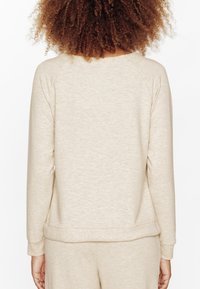 Sweatshirt beige texturé avec un col ras du cou, des manches raglan et un ourlet côtelé. Tissu doux avec une coupe décontractée.
