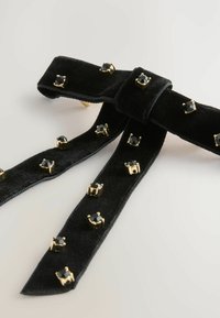 Black velvet ribbon with gold hardware accents and black stone embellishments arranged in a pattern along its length.