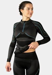 Schwarzes thermoaktive Sportbekleidungsset mit langärmeligem Oberteil mit blauen Akzenten und Reißverschluss am Hals, kombiniert mit eng anliegenden schwarzen Leggings.
