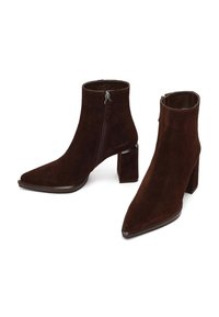 Botines de ante marrón con punta afilada y tacón ancho. Cuentan con cremallera lateral y detalles en cuero liso en las suelas.