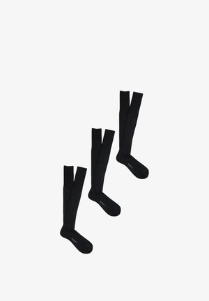 Tre paia di calzini neri alti fino al ginocchio con il marchio "PERONI" nella zona del piede, disposti diagonalmente su uno sfondo bianco.