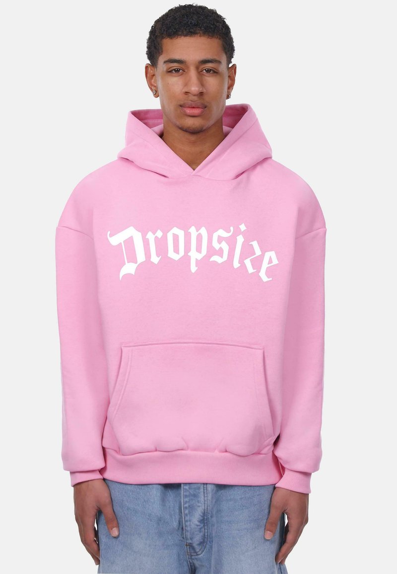Rosa Kapuzenpulli mit vorderer Tasche und Kordelzug. Mit weißem Text "Dropsie" in einer fetten, stilisierten Schriftart. Weicher Stoff.