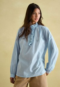 Svetlomodrá košeľa s dlhým rukávom s volánovým golierom a prúžkovaným vzorom, so zhrnutými plecami a gombíkovými manžetami, vyrobená z jemného materiálu.