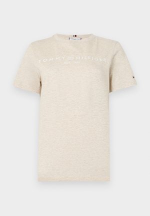 Camiseta de algodón beige de manga corta, con "TOMMY HILFIGER EST. 1985" en texto blanco en el pecho y un pequeño logotipo en la manga.