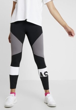 Leggings noirs et gris avec des blocs de couleur triangulaires ; bande blanche en bas ; fabriqués à partir d'un matériau extensible ; design ajusté.