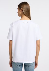 Witte katoenen T-shirt met korte mouwen, voorzien van een ronde halslijn en een kleine metalen accent aan de achterkant van de hals.