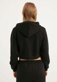 Felpa nera corta realizzata in tessuto morbido, con cappuccio regolabile, orlo a costine e maniche lunghe, dal design semplice.