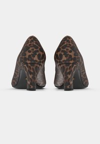 Escarpins à talons hauts à imprimé léopard, avec un bout arrondi, un tissu à texture douce et un talon bloc de hauteur moyenne. Motif noir et brun.