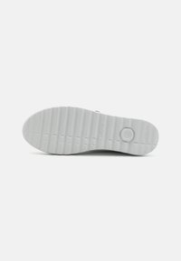 White rubber shoe sole with horizontal grooves, featuring a circular design element and embossed branding on the side. Textured surface.