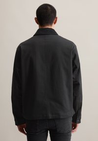 Schwarze Jacke mit strukturiertem Kragen, Rückennaht und Knopfmanschetten. Hergestellt aus strukturiertem Stoff, entworfen für eine lässige Passform.