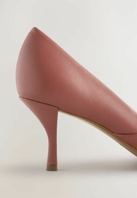Scarpa con tacco alto in pelle sintetica rosa, con punta affusolata, tacco sottile, texture liscia e design semplice, caratterizzata da una sottile cucitura decorativa.
