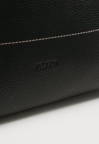 Surface en cuir noir texturé avec une fine couture blanche et un logo "PICARD" embossé au centre.