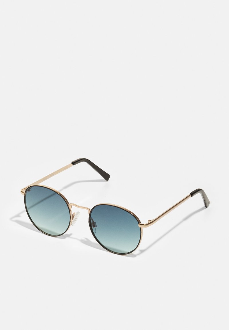 Gafas de sol redondas con marco de metal dorado, lentes degradados en azul y puntas negras. Presenta un diseño delgado con hardware mínimo.