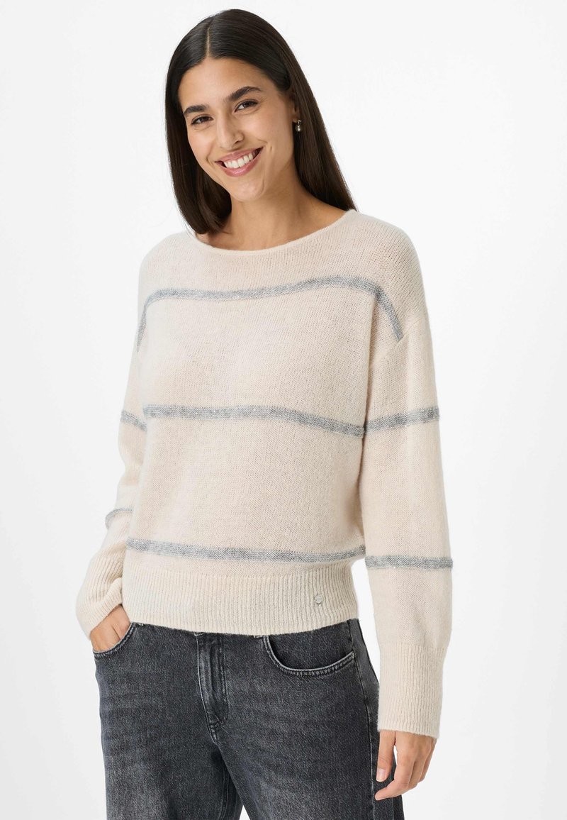 Lichtbeige trui met grijze horizontale strepen, geribbelde boorden en zoom, gemaakt van een zachte, gestructureerde stof. Gedragen met donkerdenim jeans.