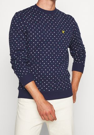 Dunkelblaues Sweatshirt mit einem Punkte-Muster aus weißen und türkisfarbenen Quadraten, gerippten Bündchen und einem kleinen gelben Logo auf der Brust.