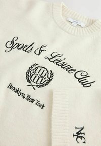 Lyscremet sweater med sort broderet tekst: "Sports & Leisure Club," et cirkulært logo og "Brooklyn, New York." Ribbet halsudskæring og manchetter.