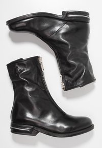 Botas de cuero negro hasta el tobillo con un diseño elegante, cremalleras laterales y punteras redondeadas; textura ligeramente arrugada; tacones bajos de bloque.