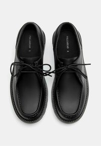 Sorte lædersko med en glat tekstur, rund tå og kontrastsyninger. De har snørebånd og en polstret inderside for komfort.