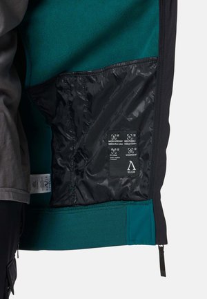 Musta takin sisäosa, jossa on tehostevärinä turkoosi fleece-vuori. Mukana vettähylkivä, hengittävä kangas ja teksturoitu helma, jossa on vetoketju.