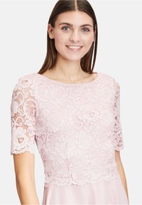 Różowa sukienka z koronkowym topem w kwiatowe wzory, krótkimi rękawami i gładką spódnicą. Dekolt jest okrągły, a całościowy design jest delikatny.
