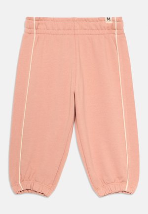 Lyserøde joggebukser laget av mykt stoff, med en elastisk midje, elastiske mansjetter og kremfargede piping langs sidene. Størrelseslabel synlig.