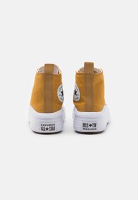 Yellow canvas high-top sneakers with white rubber soles, round logos on sides, and rear pull tabs for ease of wear.