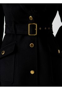 Abrigo de lana negro con un amplio cuello, botones dorados, un cinturón a juego con hebilla rectangular y dos grandes bolsillos delanteros.