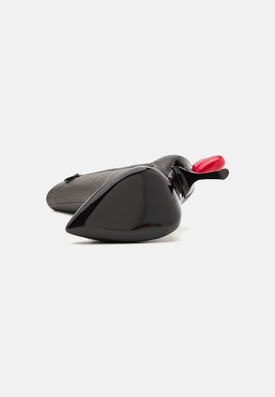 Black patent leather high heel shoe with a pointed toe and red accent on the heel, featuring a sleek, glossy finish.