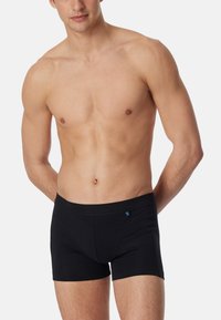 Zwarte boxershorts van zacht materiaal met een slim fit ontwerp, voorzien van een naadloze tailleband en een klein logo detail aan de voorkant.