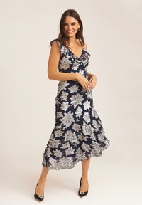 Navy dress with silver floral embroidery, ruffled neckline, and a flared hem. Paired with black high heels featuring decorative accents.