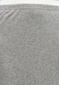 Tissu gris clair à côtes présentant une texture subtile. Le matériau est doux et légèrement extensible, avec une ceinture blanche en haut.